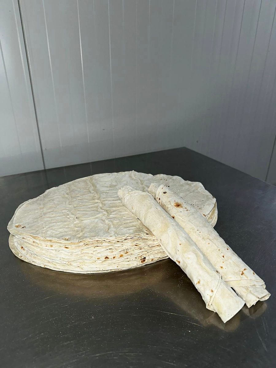 A round stack of dürüm lavaş on a stainless steel work table in the bakery