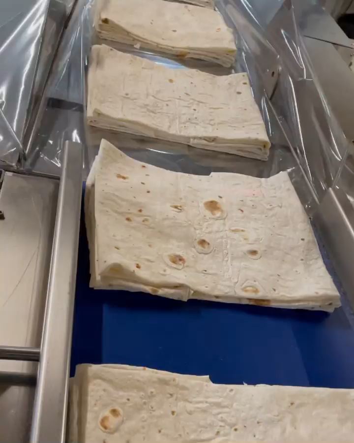 Mavi taşıma bandında katlanmış yufka paketleri, folyonun altına doğru ilerliyor